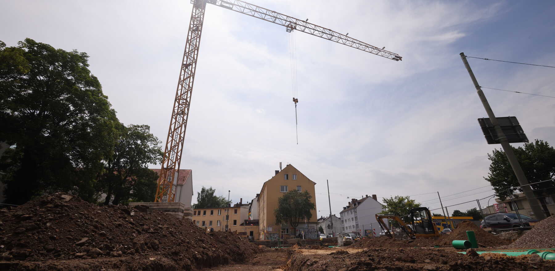 Baustelle in der Stadt mit Kran, Bäumen und einem planierten Bauplatz