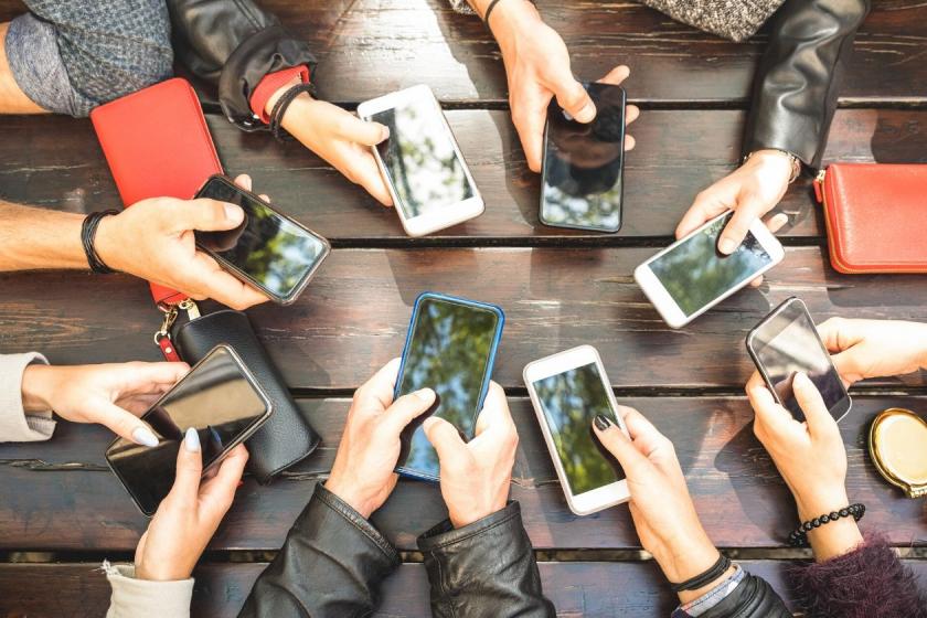 Eine Gruppe von Freunden sitzt mit ihren Smartphones an einem Tisch
