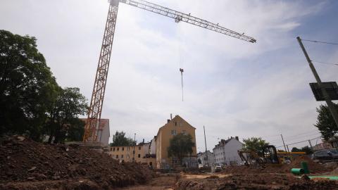 Baustelle in der Stadt mit Kran, Bäumen und einem planierten Bauplatz